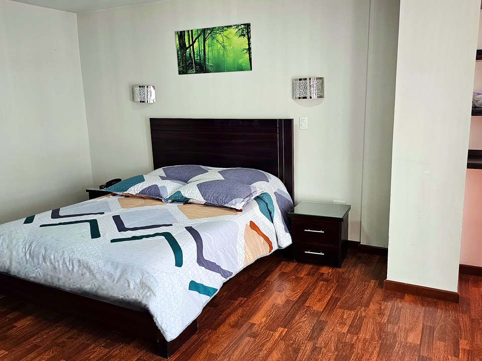 Habitación doble del Hotel Avanty: una cama doble, mesa de noche y piso en madera