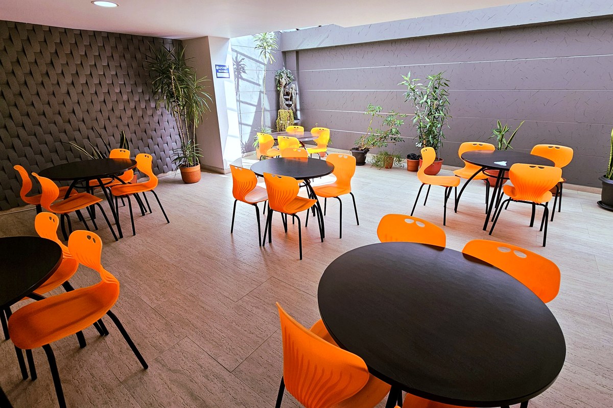 Comedor del Hotel Avanty con mesas redondas y sillas naranjas